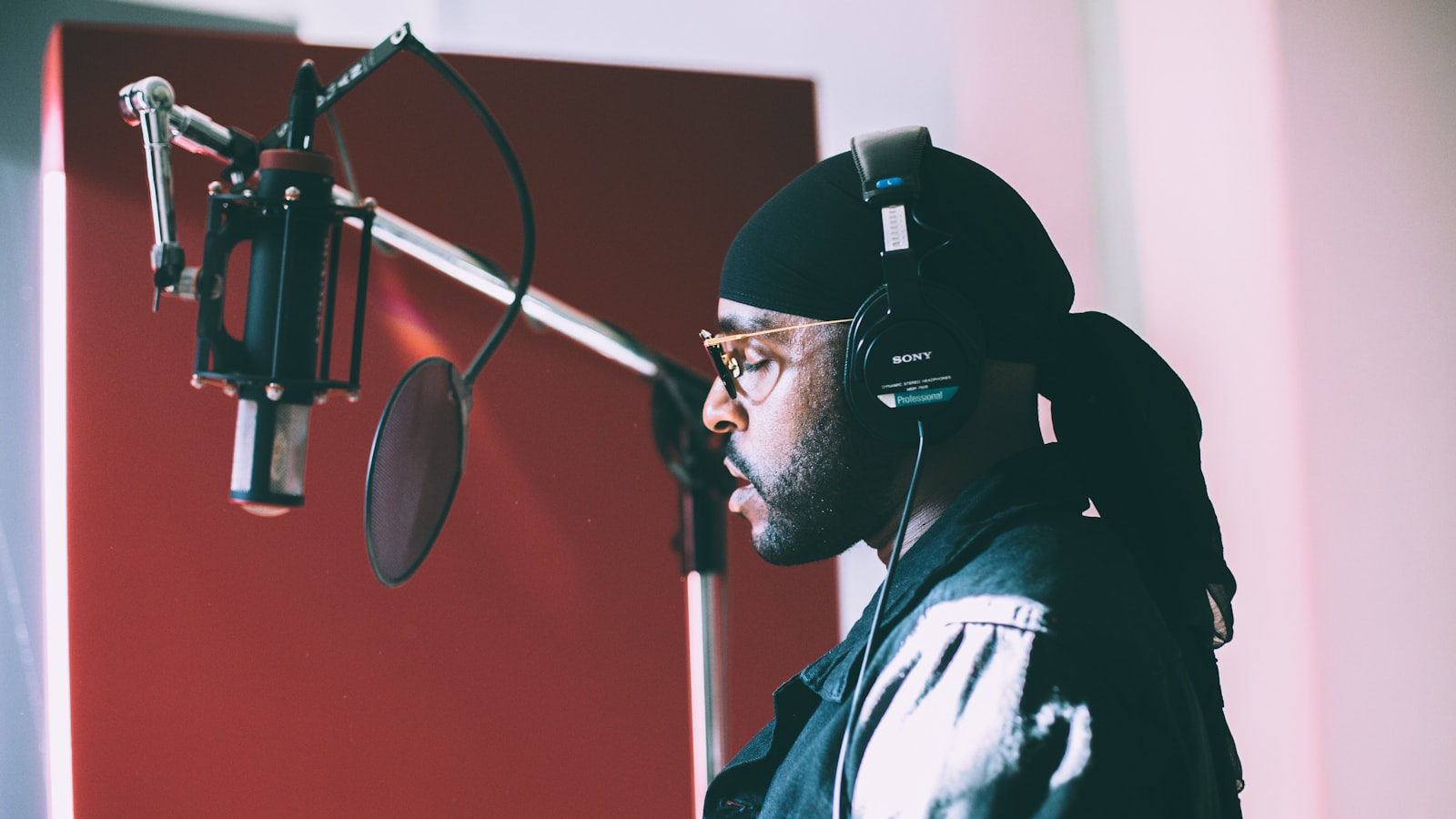 Singer wearing headphones recording vocals at a studio condenser microphone, the session work behind custom radio jingles