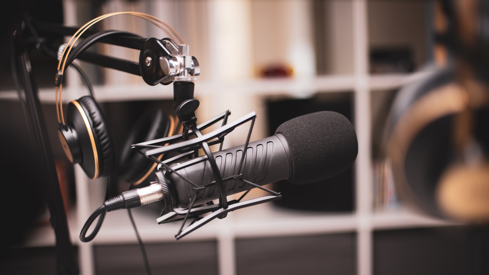 Broadcast microphone on a boom arm with studio headphones behind it, the on-air setup where radio segment names get said out loud every day
