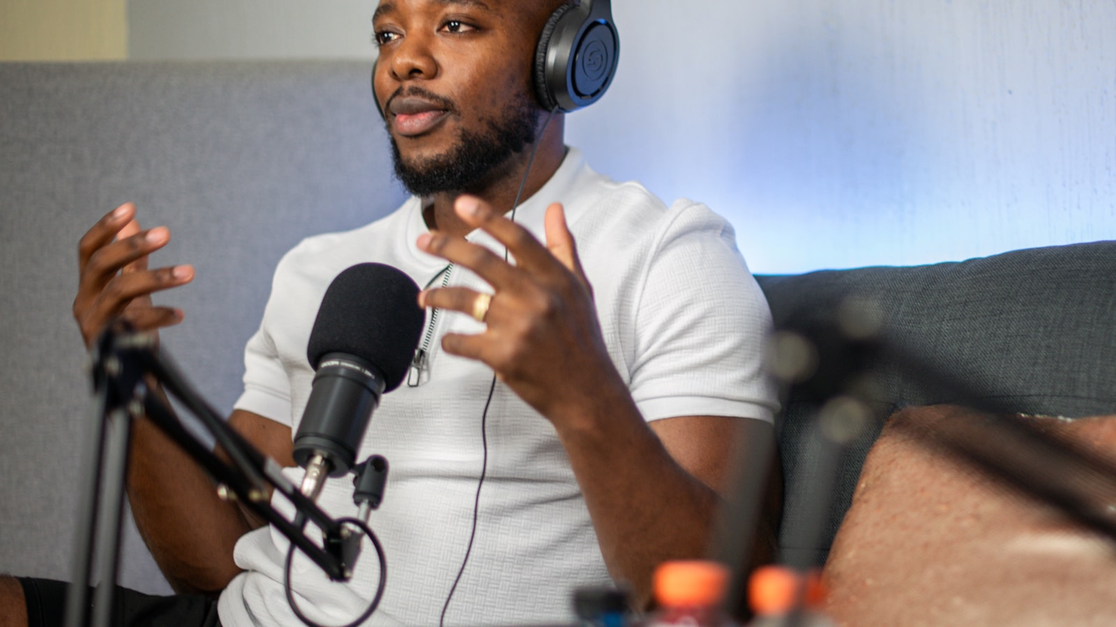 Radio talent wearing headphones talking into a studio microphone mid-break, the visible part of what a radio DJ does all day